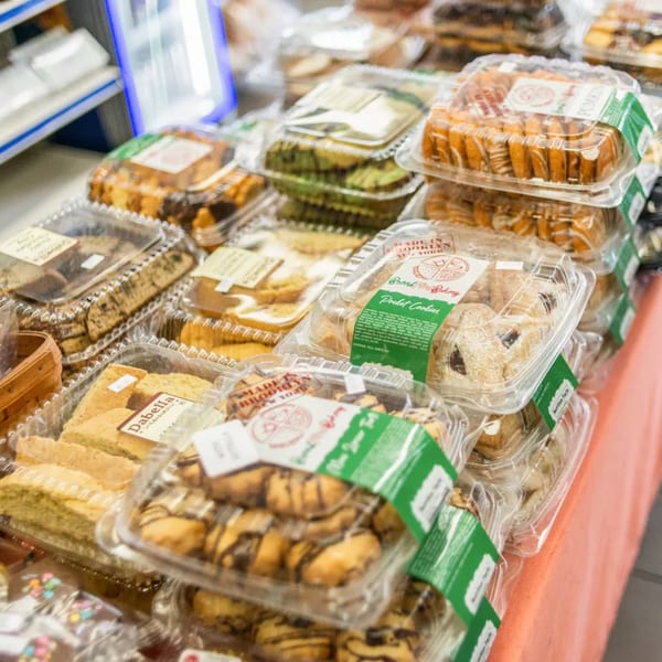 Numerous clear plastic containers filled with various baked goods, including cookies and biscotti, on display.